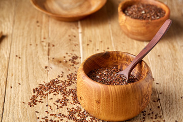 Flax seeds in wooden bowl and spoon on rustic wooden background, top view, shallow depth of field