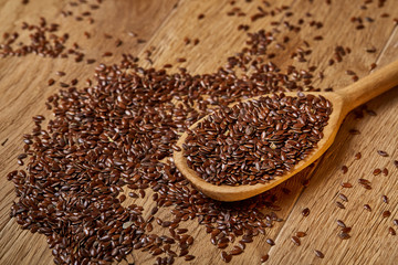 Wooden spoon with flax seeds on rustic background, top view, close-up, shallow depth of field, selective focus
