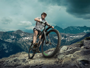 Fototapeta premium Man in helmet and glasses stay on the bicycle under sky with clo