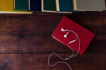 Books, White Headphones on a Dark Wooden Background. Flat lay, top view