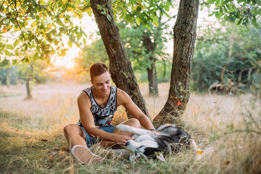 young male playing with his siberian husky dog in park