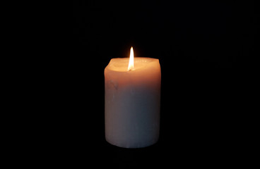 candle burning in darkness over black background