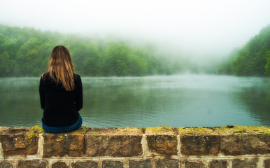 Obraz premium girl sitting looking at the landscape in a lake