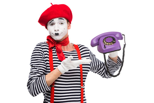 skeptical mime showing at ultra violet retro stationary telephone isolated on white