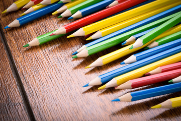 Fototapeta premium Different colored pencils on the brown wooden table background .Top view .Close up .Color .Pencil.Set