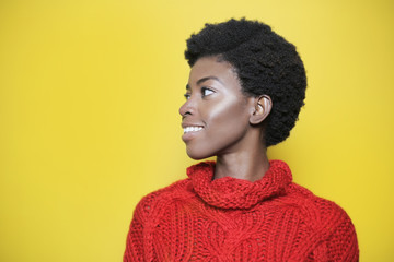 Beautiful girl wearing a red sweater in front of a yellow wall