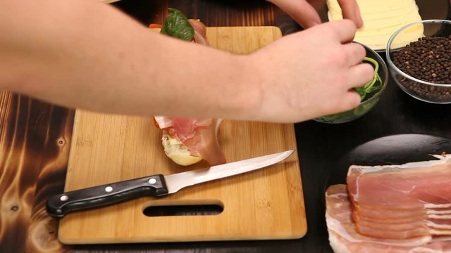 Placing letuce on healthy sandwich in the kitchen on wooden board