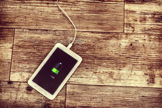 Tablet Charging On A Wooden Floor