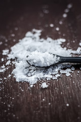 Close up of aurvedic herb camphor powder in a small spoon on brown wooden surface in dark Gothic colors is helps in Prevents Skin Infections,Eliminates Gas,Reduces Nervous Disorders,Increases Libido.