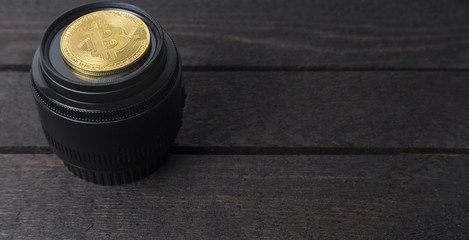 bitcoin and camera lens lay on wooden background