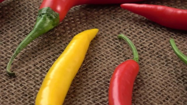 Fresh chili peppers - yellow, green and red chili pepper on brown background.