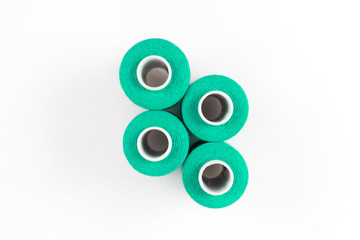 Four green sewing threads on white coils on white background. Sewing supplies