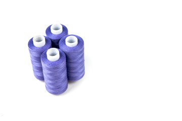 Four medium purple sewing threads on a white coils on a white background. Sewing supplies