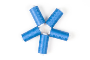Five blue sewing threads laying in a circle on a white background, sewing accessories