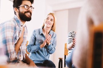 Young persistent handsome guy sharing a good news with other participants on special group therapy.