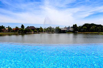 Fototapeta na wymiar Beautiful outdoor swimming pool beside village lake with clear sky and cloudy.