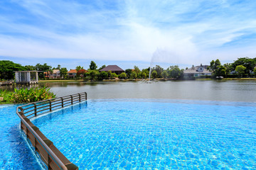 Beautiful outdoor swimming pool beside village lake with clear sky and cloudy.