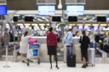 Abstract blur and bokeh passengers check in at counter serviced by ground at international airport. Background with copy space.