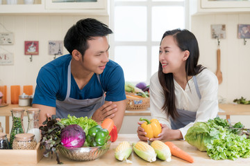 Young Asian couple preparing food together at counter in kitchen. Happy love couple concept.