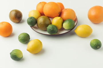 Raw citruses on plate on white background