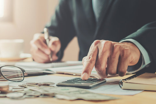 accountant using calculator to calculate of money budget on desk in office. business finance and accounting