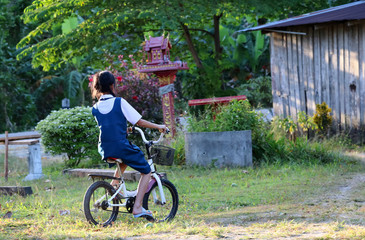 Obraz premium Asian students girl wearing school uniform, enjoy a bicycle in local village in the evening