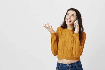 Happy trendy caucasian woman speaking with excitement via smarpthone, gesticulating as if...