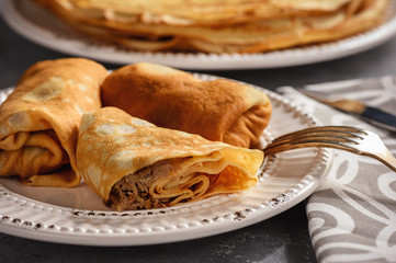 Pancakes stuffed with meat, on dark background.