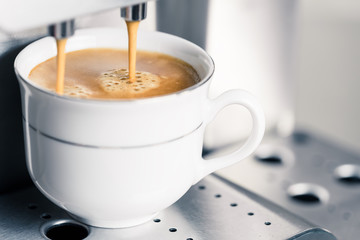 Creamy coffee pouring into a cup
