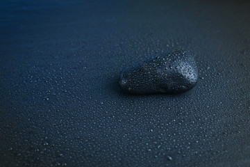 Stone with a lot of water droplets on dark blue background