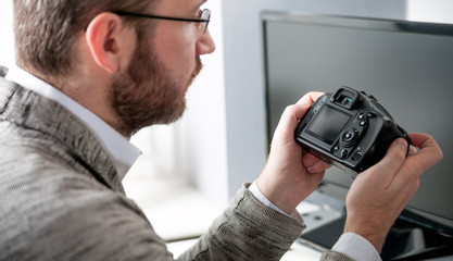 Photographer in home office working with laptop and looking at camera