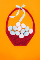 top view of easter eggs on made of sand basket with bow isolated on orange