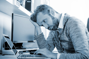 Tired man at workplace in office being unhappy