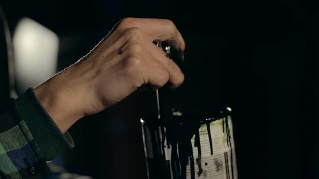 Closeup shot of painter's hand stirring a paint in a jar