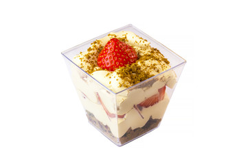 Creamy cream dessert in a plastic cup decorated with berries on a white background. 