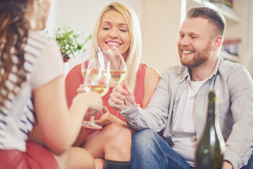 Friends cheering with wine at house party. 