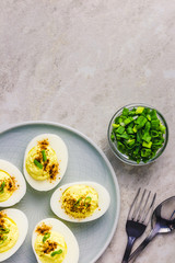 Classic deviled eggs with paprika and chives on white background. Top view, copy space.
