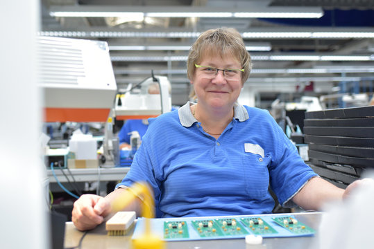 &auml;ltere Arbeiterin in einer Fabrik zur Montage von Elektronik // senior female worker in an electronics assembly factory