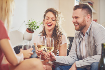 Fototapeta premium Friends cheering with wine at house party. 
