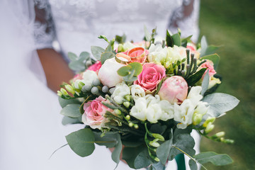 Bride holds rich pink wedding bouquet in her arms posing outisde