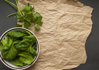 Fresh parsley and spinach leaves in a bowl on paper background with text space. Healthy food...
