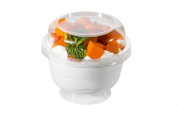 Creamy cream dessert in a plastic cup decorated with berries on a white background. 