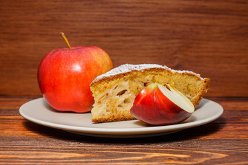 Fresh apples and a piece of apple pie sprinkled with powdered su