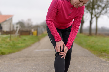 Woman jogger clutching her injured knee