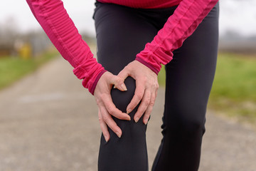 Woman jogger clutching her injured knee