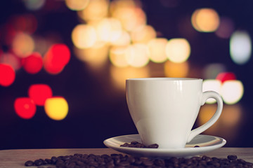 cup of coffee on wooden table with defocus bokeh of coffee shop background. Image with soft focus and blurred background.