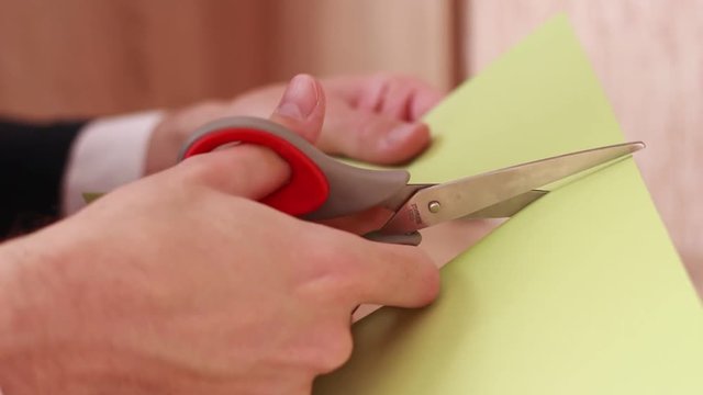 Cutting green blank sheet of paper with scissors
