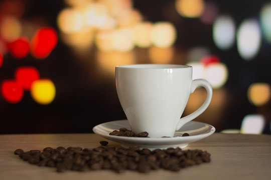 cup of coffee on wooden table with defocus bokeh of coffee shop background. Image with soft focus and blurred background.