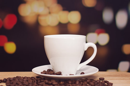 cup of coffee on wooden table with defocus bokeh of coffee shop background. Image with soft focus and blurred background.