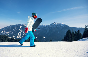 one snowboarder with snowboard walking on winter mountain top